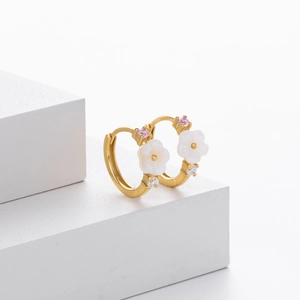 Close-up of gold flower earrings with white petals and micro-set zircon stones