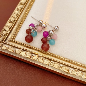 Detail of bohemian clustered cat eye stone earrings with colorful beads and silver studs