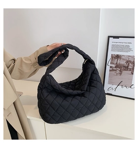 Detail of black quilted nylon dumpling bag featuring a knotted shoulder strap design