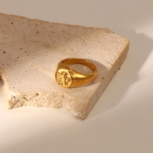 Detail view of a vintage gold angel relief signet ring on a natural stone base