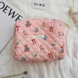 Trousse de maquillage matelassée rose avec motifs d'ours parmi des accessoires variés