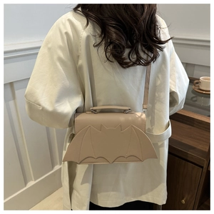 Detailed back view of a beige bat-winged crossbody bag with top handle and strap