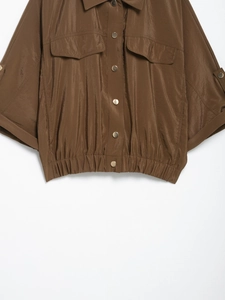 Détail d'une chemise safari marron avec boutons-pression en métal et taille élastiquée