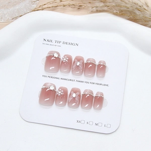 Detailed set of 10 handmade press-on nails with butterfly and pearl charms on white tray