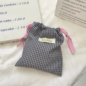 Detail of small gingham drawstring pouch with pink cotton cord and branded woven label