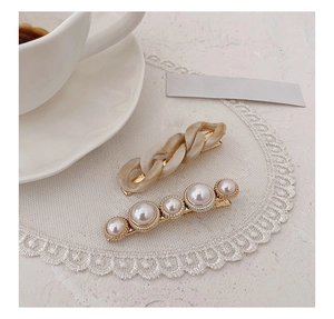 Detail of cream chain and white pearl hair clips on white lace with elegant vibe