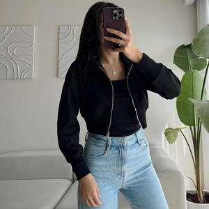 Detail of black zip-up cropped hoodie with metal zipper and ribbed long sleeves