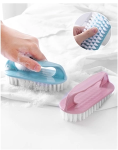 Close-up of handheld cleaning brush with soft bristles scrubbing soapy fabric surface
