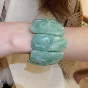 Detail of green and white marbled acrylic stretch bracelet on woman's wrist