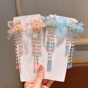 Detailed view of floral hair clips with ribbon bows and dangling pearl tassels