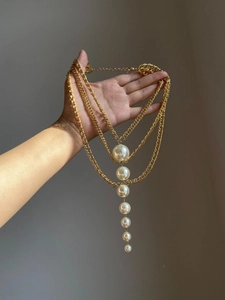 Detail of layered gold chains featuring seven gradient white pearls on a stylish necklace