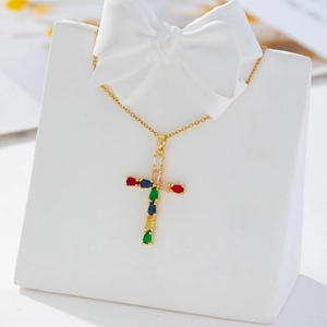 Detail of gold cross pendant necklace with colorful zircons on an elegant display stand