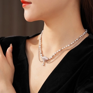 Detail einer zweireihigen Perlenkette mit fächerförmigem Anhänger und Wassertropfen-Charm