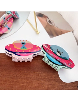 Detail view of pink and teal UFO acrylic hair claws with colorful cartoon star patterns