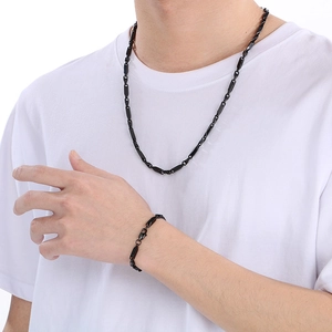 Gros plan d'un ensemble collier et bracelet gourmette en acier titane noir