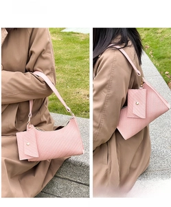 Close-up of pink embossed leather underarm bag set with a mini pouch on model