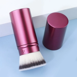 Detail of retractable makeup brush with magenta metallic handle and dual-tone bristles