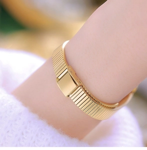 Macro detail of gold stainless steel mesh watch band and smooth folding clasp on the wrist