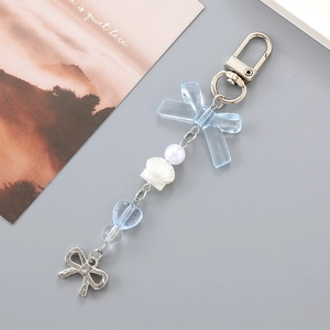 Detail of silver keychain with blue bow, pearl, shell pendant and heart bead