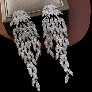 Detail of silver leaf tassel earrings with white zircon crystals on dark jewelry box