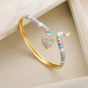 Detail of bohemian gold snake bracelet with colorful enamel stripes and zircon pave setting