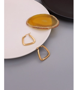 Detail shot of chunky U-shaped gold geometric earrings on white marble display
