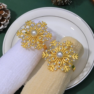 Close-up of golden snowflake napkin rings with rhinestones and pearls on a festive plate