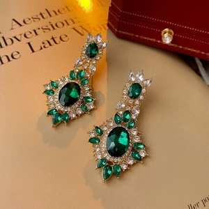 Macro detail of emerald oval earrings with crystal inlay on an open vintage book page