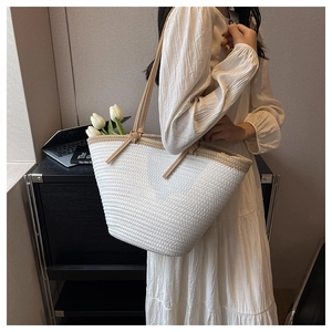 Detail shot of the woven texture and contrast handles on a large summer beach tote bag