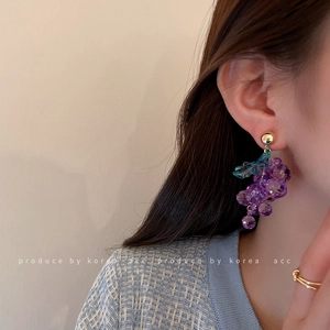 Exquisite purple grape-shaped bead earrings with gold leaf detail worn by a model