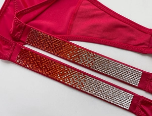 Macro detail of gradient rhinestones on rose red fabric for fitness thong underwear