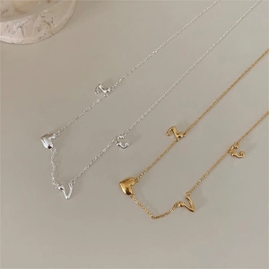 Detailed close-up of gold and silver sterling silver necklaces with heart and letter charms