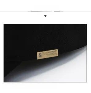 Detail of black cotton baseball cap showing a bronze SPORT metal plaque on the brim