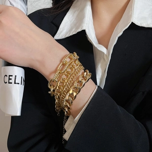 Close-up of layered gold chain bracelet set on wrist with Cuban and textured links