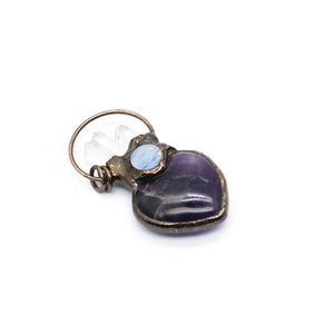 Close-up of handmade copper wire-wrapped pendant with heart amethyst and blue stones