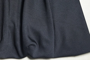 Close-up of elegant black dress fabric showing detailed twill weave and smooth texture