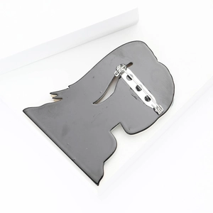 Detail view of the black acrylic brooch back featuring a secure metal safety pin closure