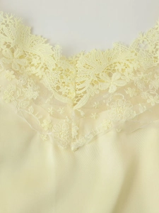 Détail du décolleté en dentelle jaune pâle et tissu satiné du caraco