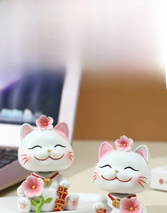 Macro detail of cherry blossom lucky cat figurine with peaceful blessing text