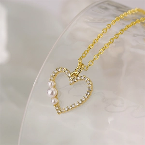 Vue macro d'un collier cœur doré orné de perles blanches et de diamants brillants