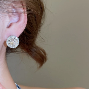 Detail view of round cubic zirconia stud earrings with micro-pave halo on a model ear