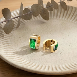 Close-up of gold-plated stainless steel earrings featuring emerald-green rectangle stones