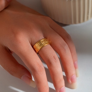 Close-up of 18K gold-plated stainless steel ring with embossed Evil Eye pattern on model