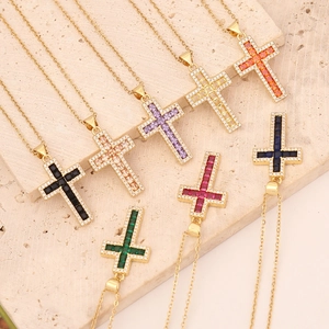Cross pendant necklace with colorful micro-inlaid zirconia on a stone surface