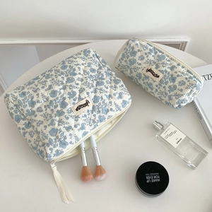 Minimalist blue floral quilted cosmetic bag set with makeup brushes on white desk