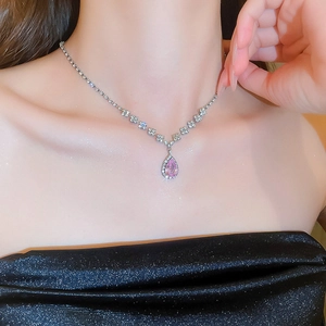 Close-up of elegant silver necklace with pink teardrop crystal pendant on model's neck