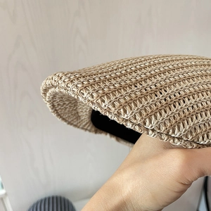 Dettaglio della trama in paglia intrecciata traspirante di una coppola beige con fascia interna