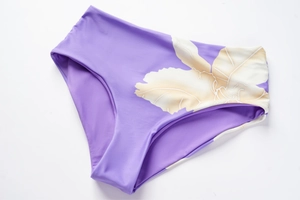 Vista macro dello slip bikini viola a vita alta con stampa floreale tropicale e cuciture fini