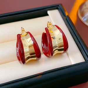 Gros plan de boucles d'oreilles créoles émaillées rouges dorées dans un écrin à bijoux