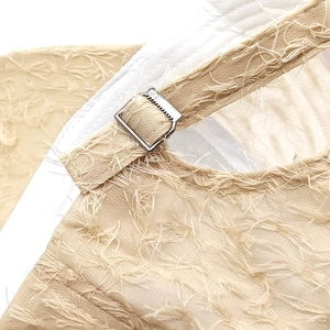 Detail of light apricot lace baseball cap showing feather-like fringe texture and metal buckle